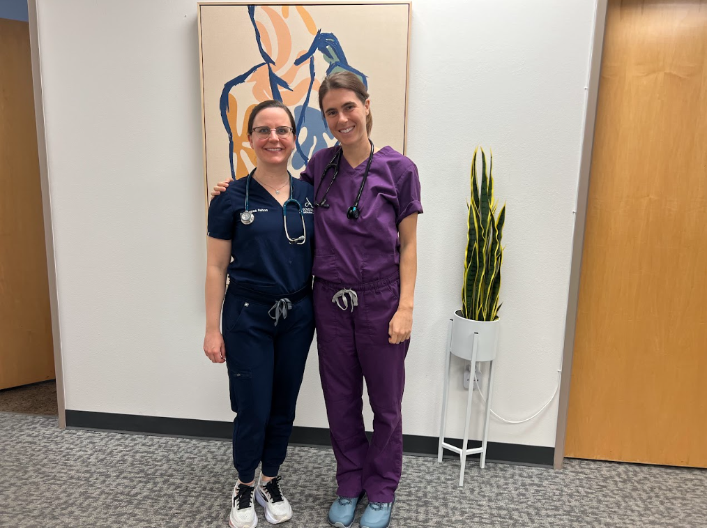 Two doctors in scrubs standing together in the clinic hallway